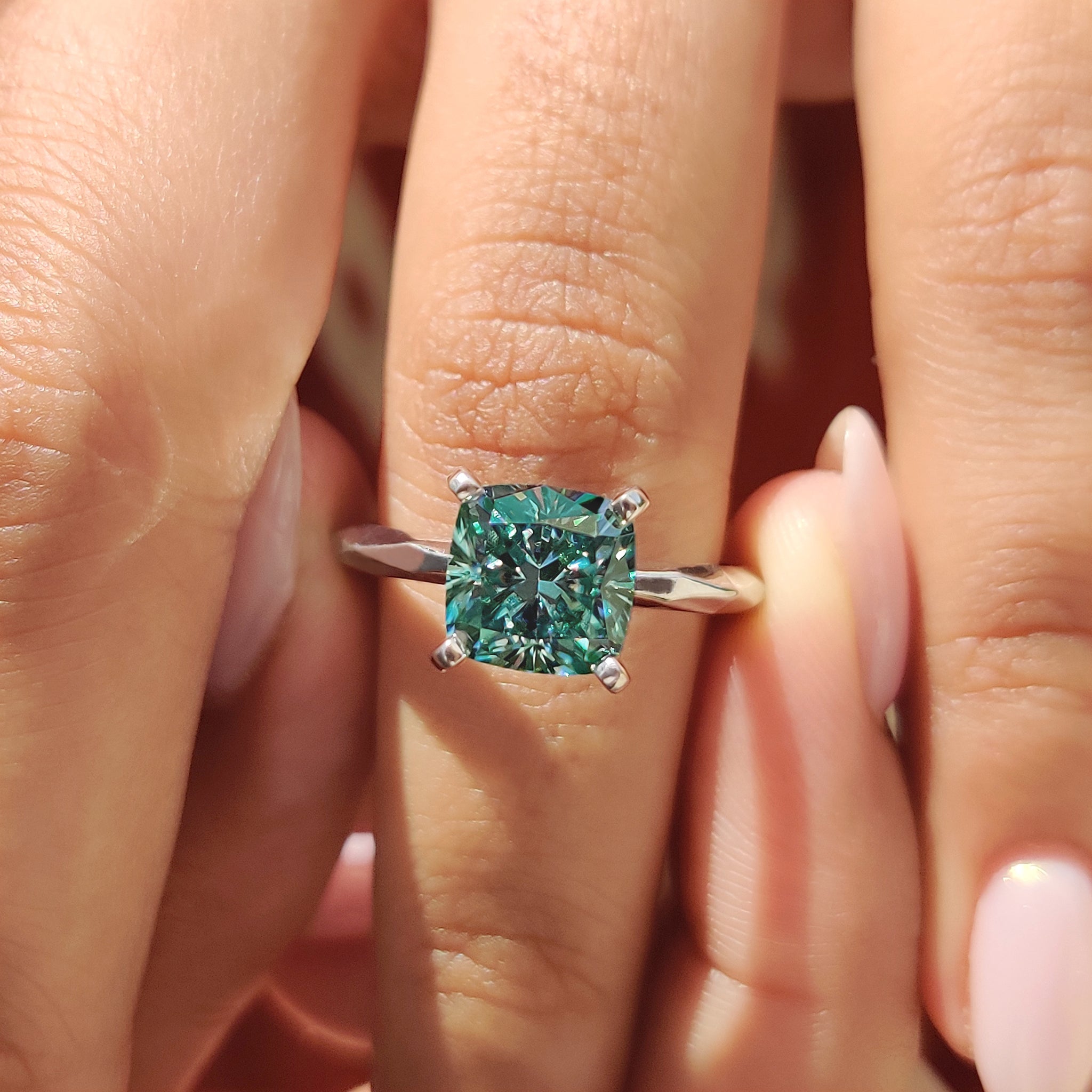 Cushion cut engagement ring featuring cyan blue moissanite in a solitaire setting.