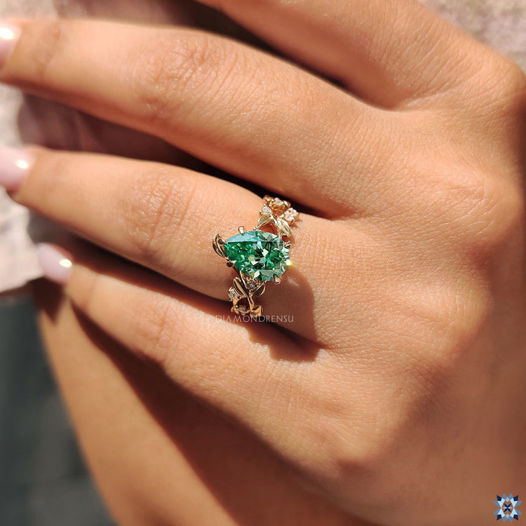 Green pear cut moissanite ring with 5 claw prong and custom nature motif setting.