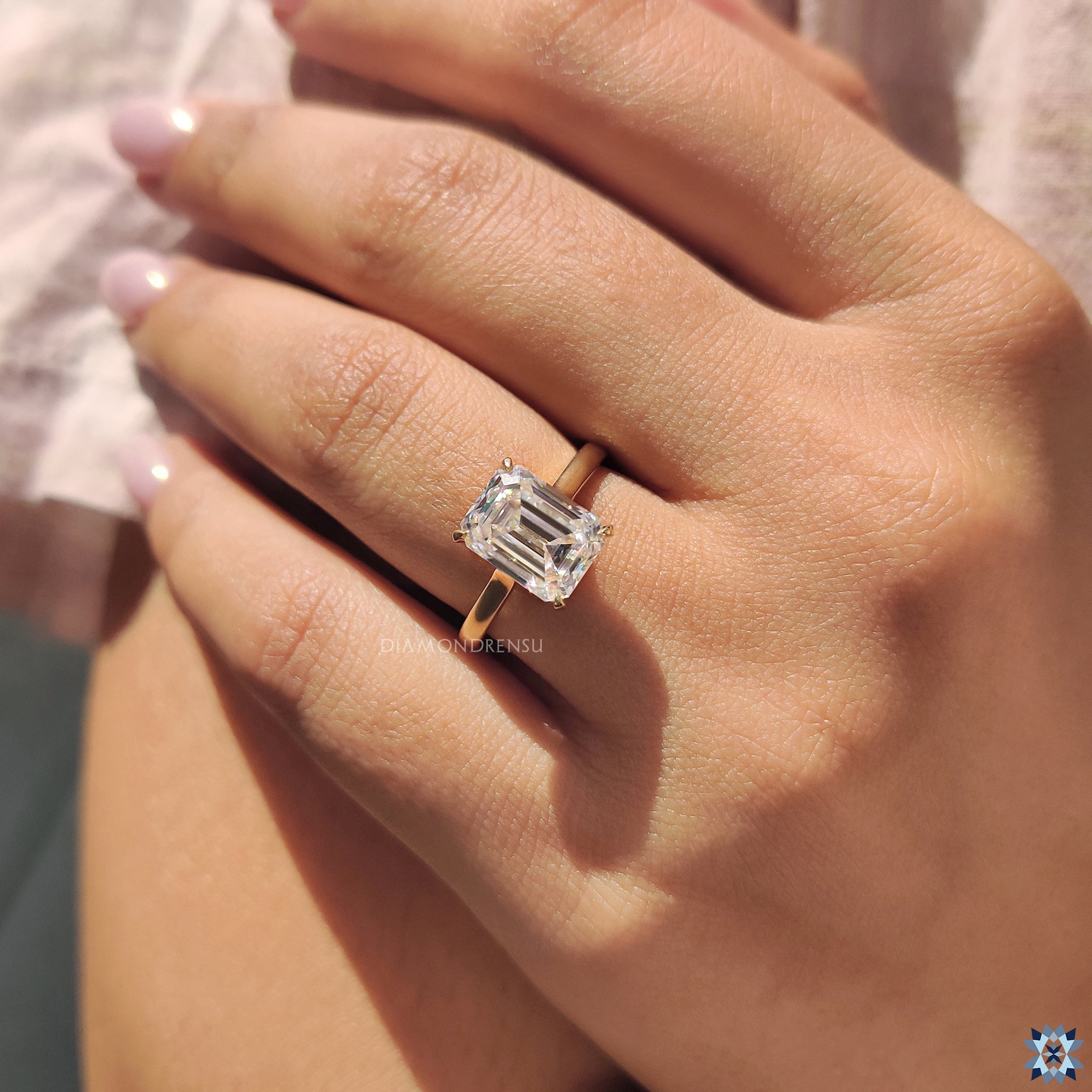 Cathedral setting moissanite ring with emerald cut stone and handcrafted yellow gold band.