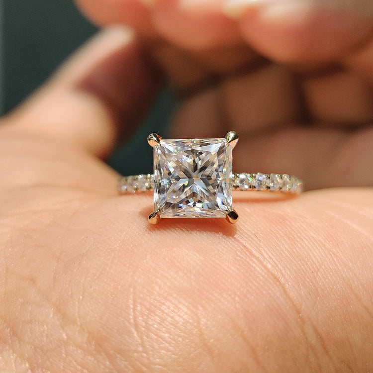 Moissanite gold ring with princess cut stone and round cut pave band in yellow gold.