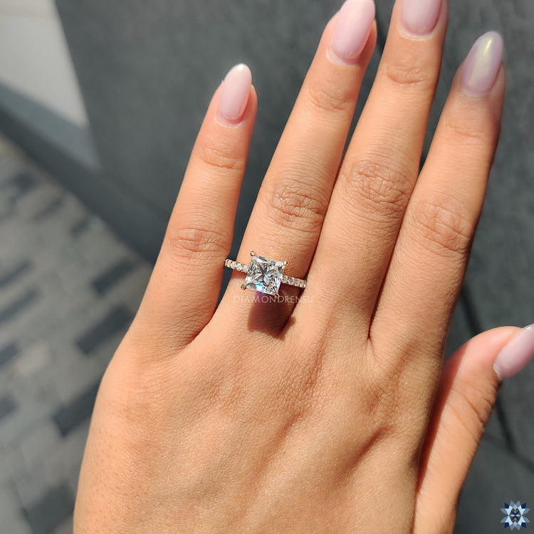 Yellow gold engagement ring featuring princess cut Moissanite and round pave setting.