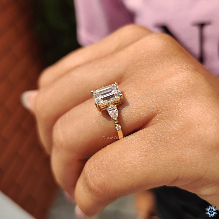 Buy engagement ring with emerald moissanite and pear cut accents in gold.