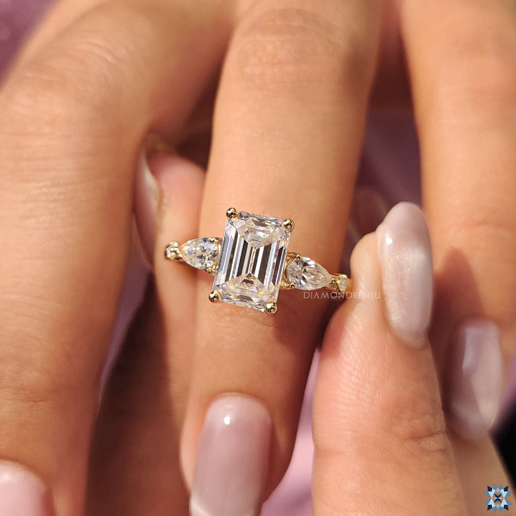 Moissanite emerald cut ring in yellow gold with side pear cut stones.