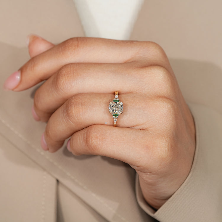 Cushion diamond ring with green emerald side stones.