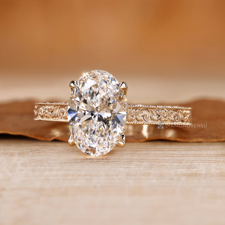 Oval diamond ring with floral engraved shank.