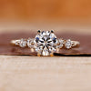 Side stone engagement ring crafted with round diamond center.