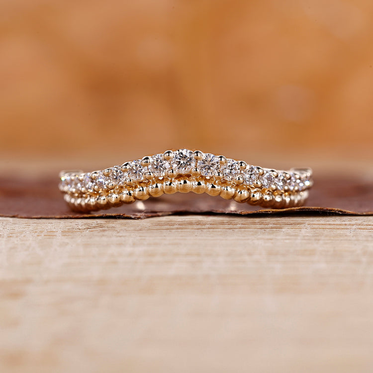 Curved diamond wedding band with round stones and milgrain detailing.