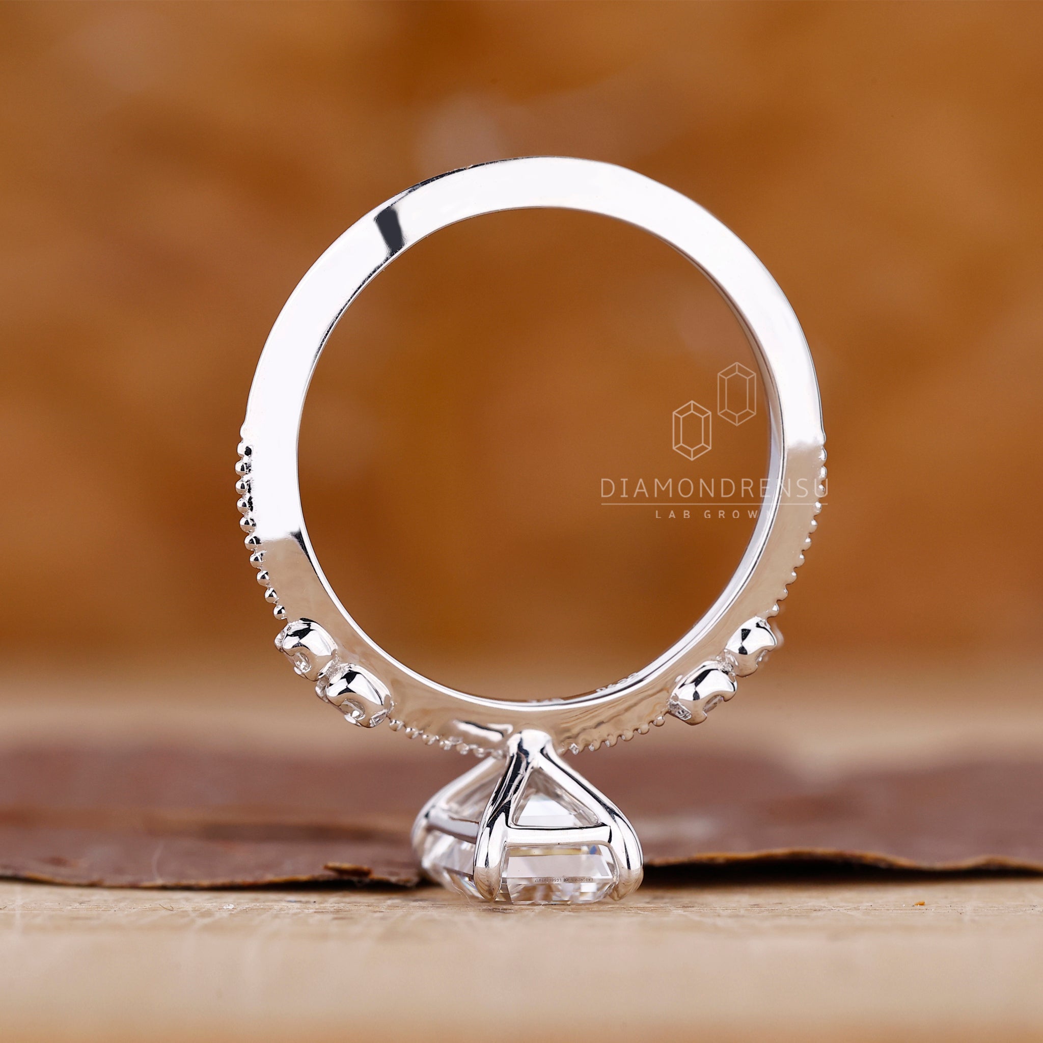 4 claw prong ring holds emerald diamond in place.