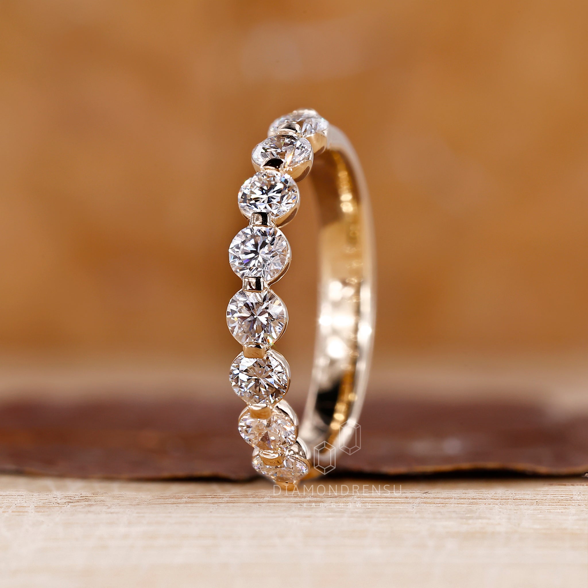 Buy wedding band featuring shared prong setting and clean gold finish.