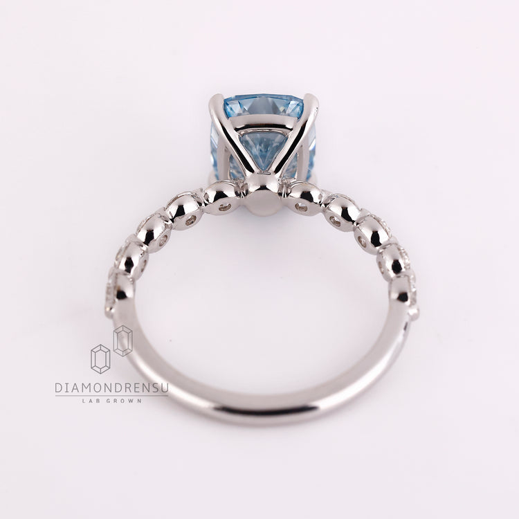 Lab grown blue diamond ring with round pave accents.