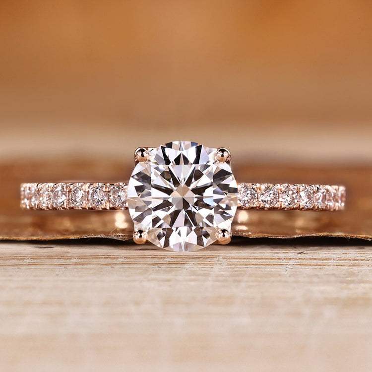 Round cut engagement ring with round pavé diamond details.