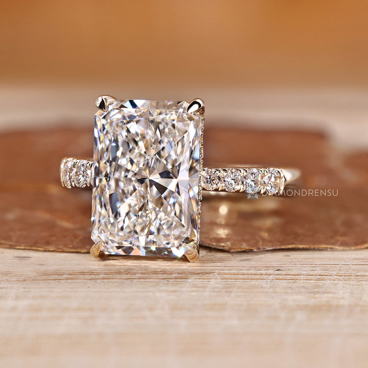 Radiant cut engagement ring with round diamond side stones.