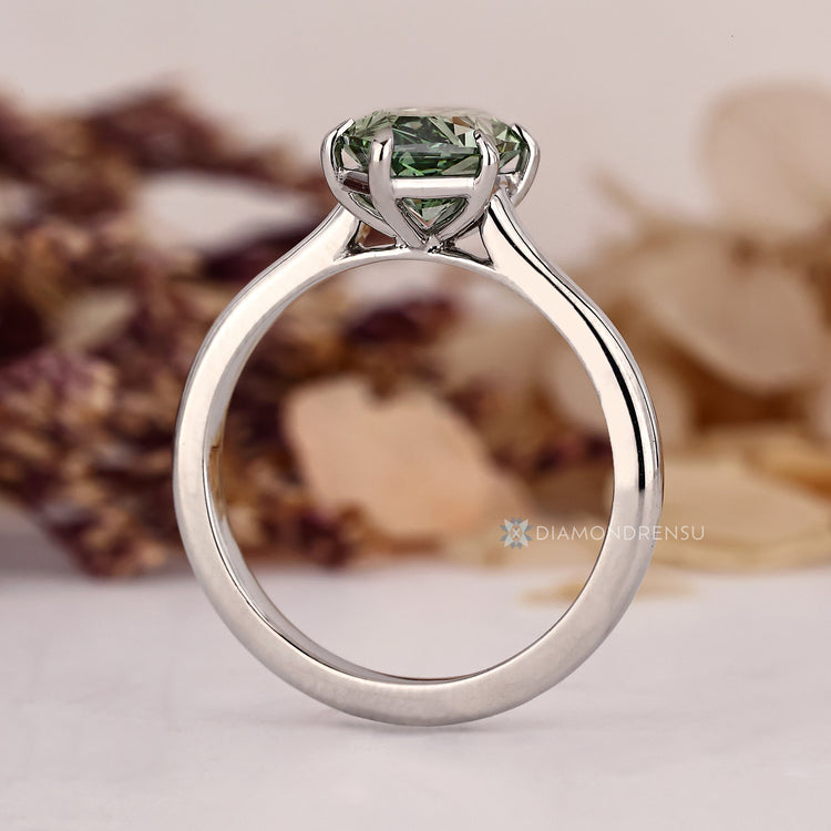 Green diamond engagement ring with six claw prong setting.
