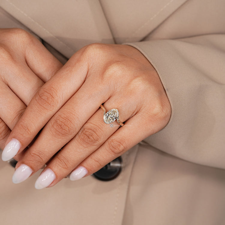 Oval engagement ring with bypass setting and milgrain details.