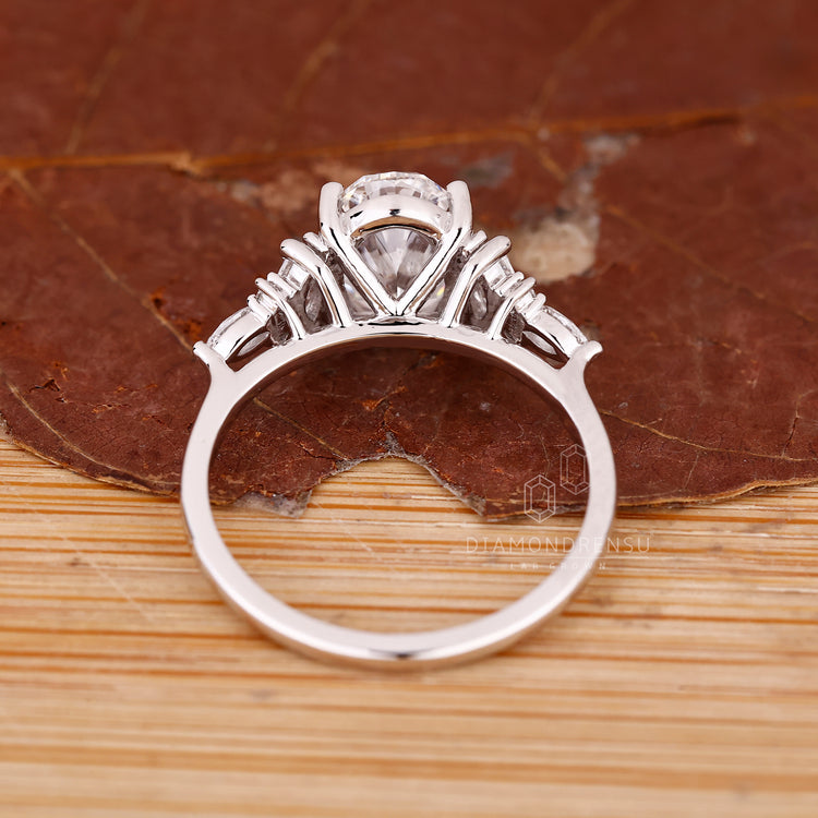 Oval engagement ring with marquise side stones and prongs.