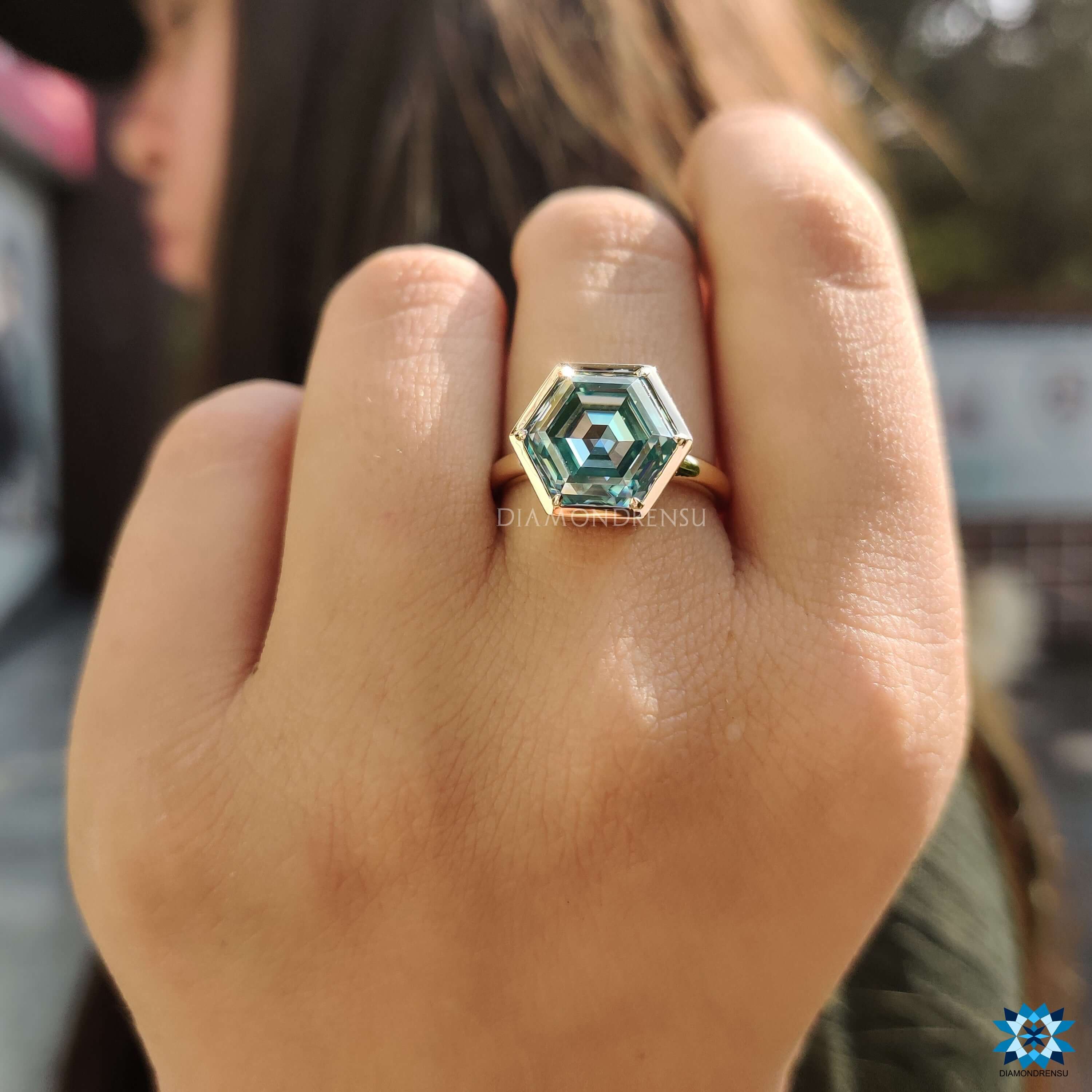 Hexagon cut cyan blue moissanite ring in yellow gold bezel setting.