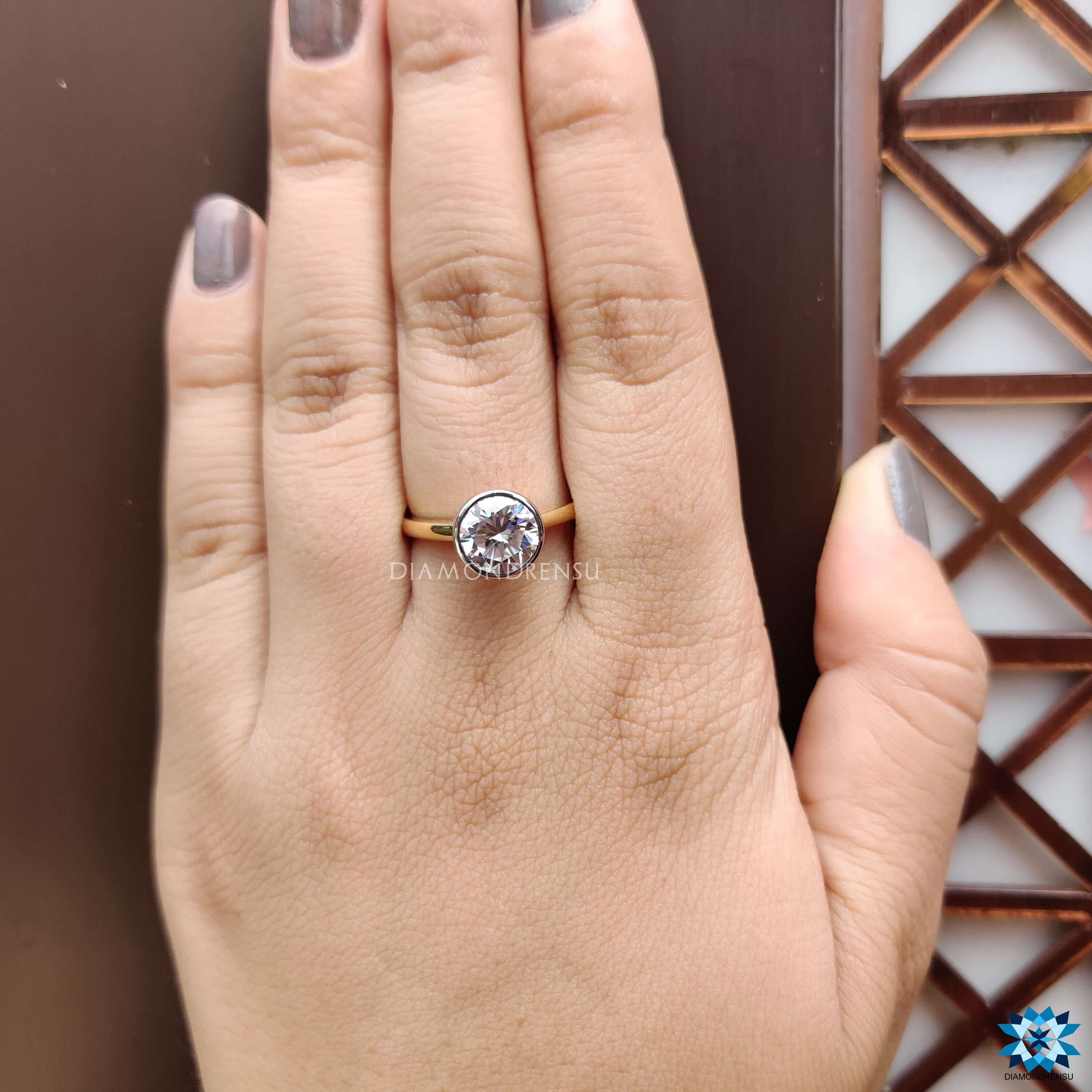 Hidden halo engagement ring with round bezel setting.