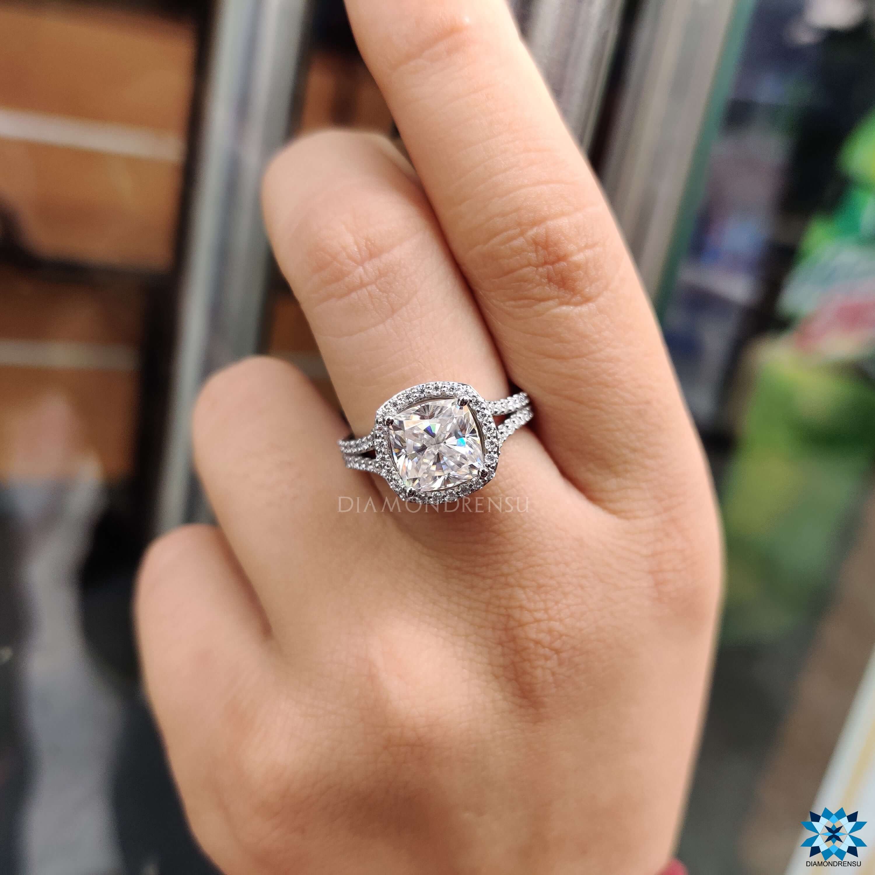 Halo engagement ring with cushion cut moissanite center.