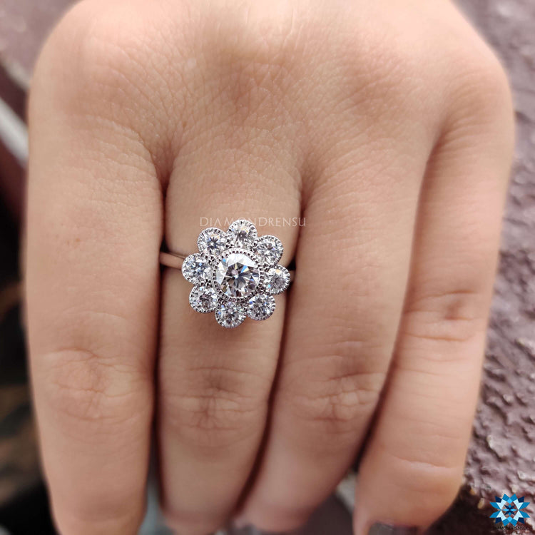 White gold engagement ring featuring milgrain bezel setting and round side stones.