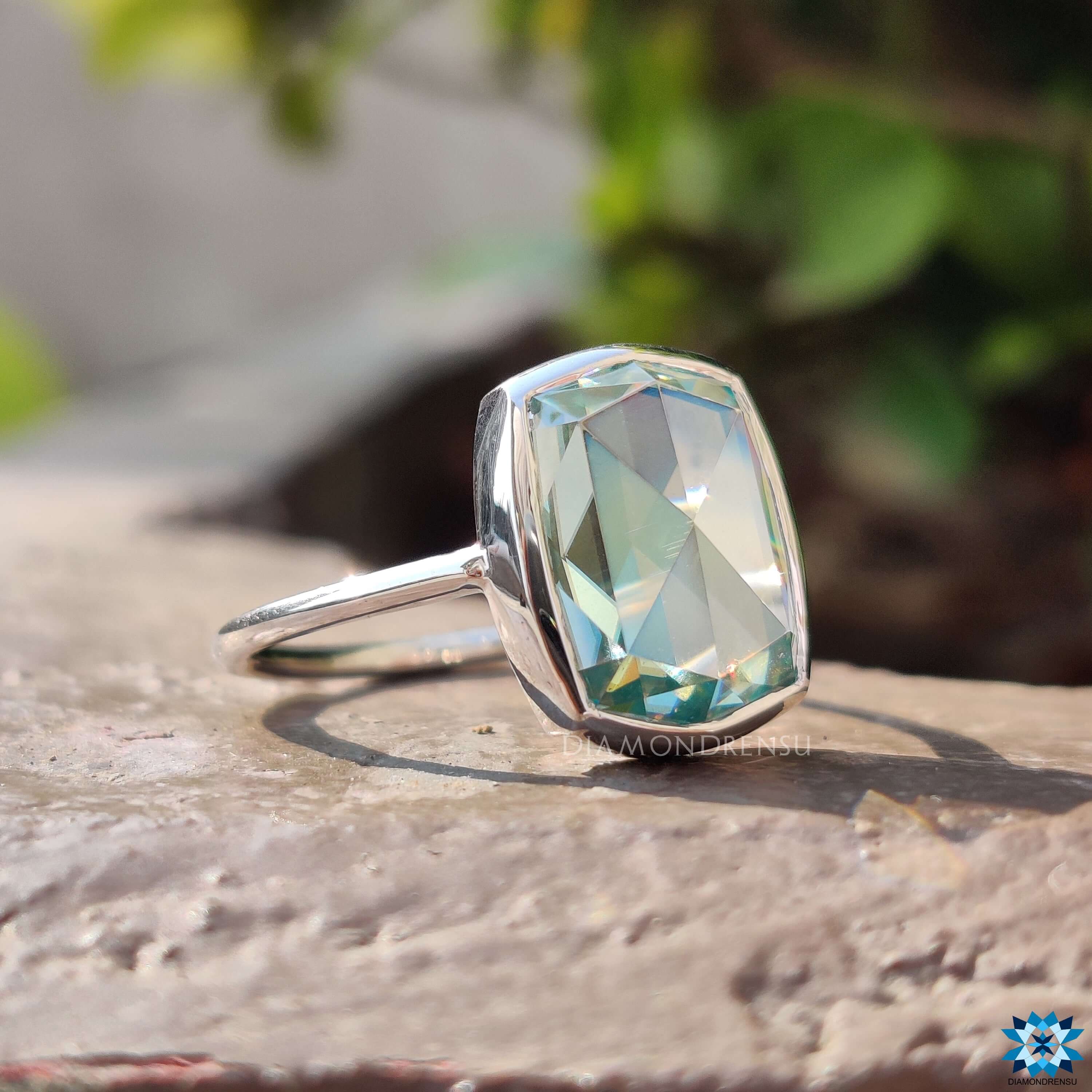 Handmade engagement ring with bezel-set cyan blue moissanite center.