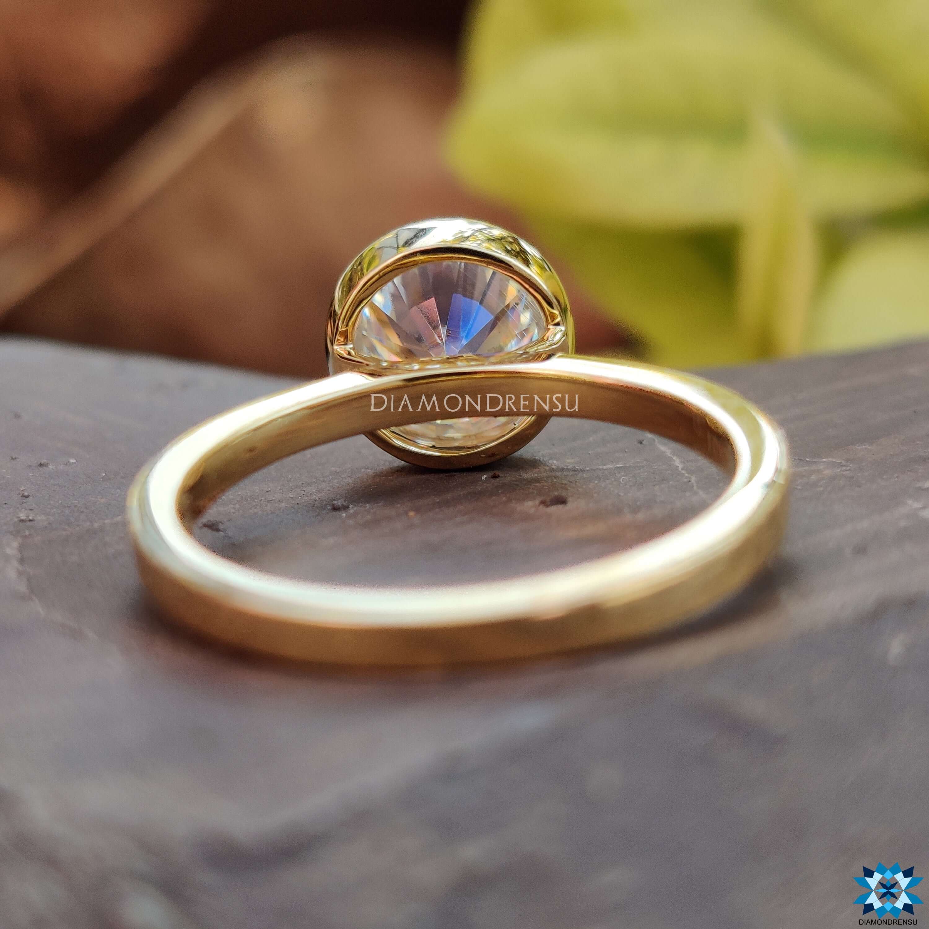 Yellow gold bezel Moissanite ring featuring round cut solitaire design.