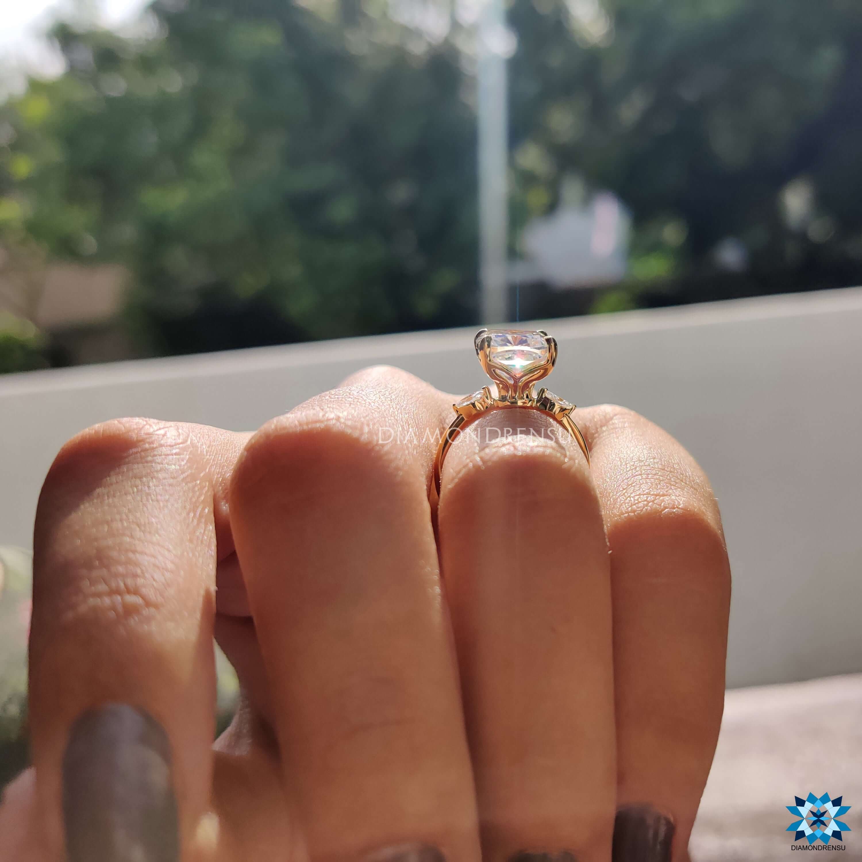 Handmade ring with three moissanite stones set in a 4 prong yellow gold setting.