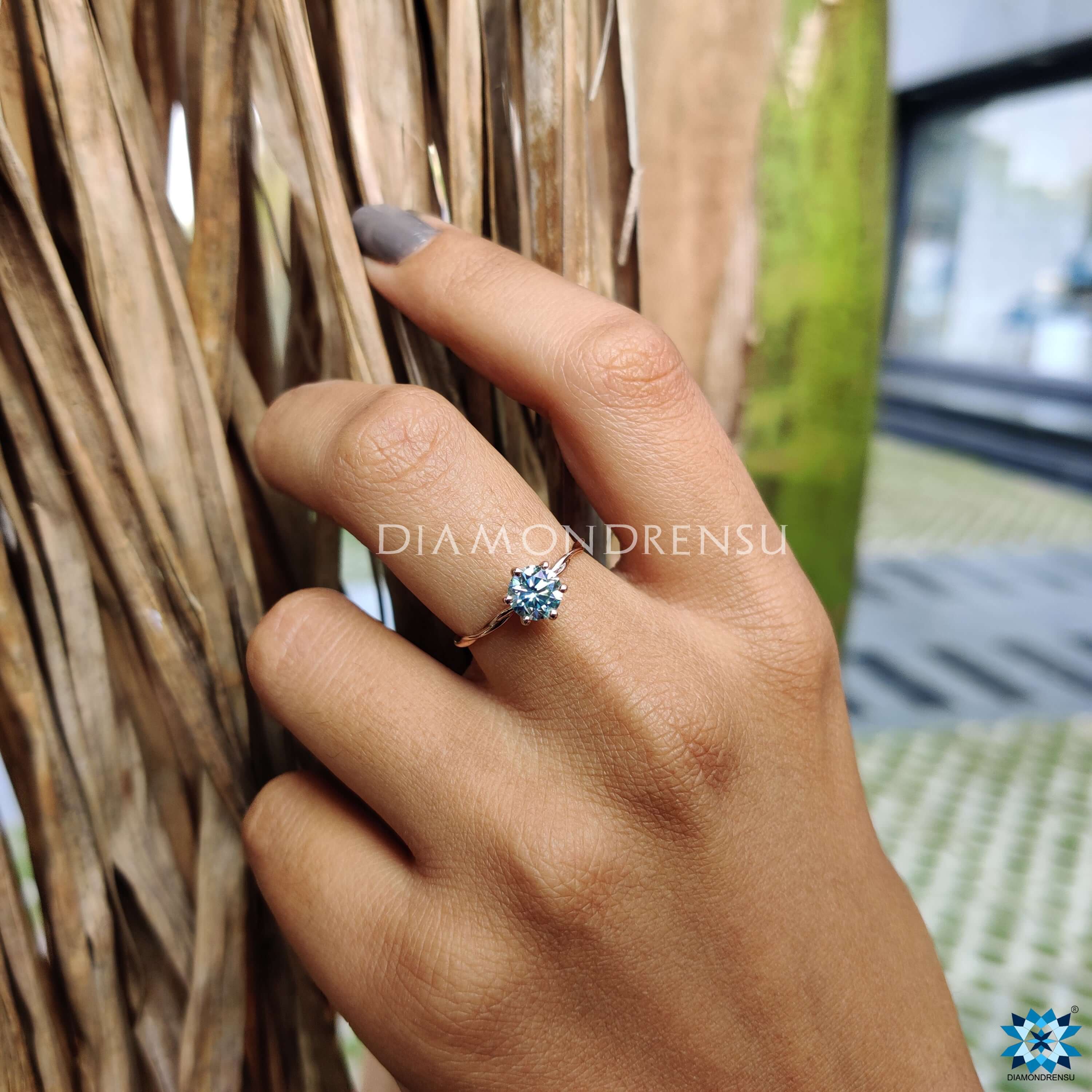 Solitaire engagement ring with a twisted rose gold band.