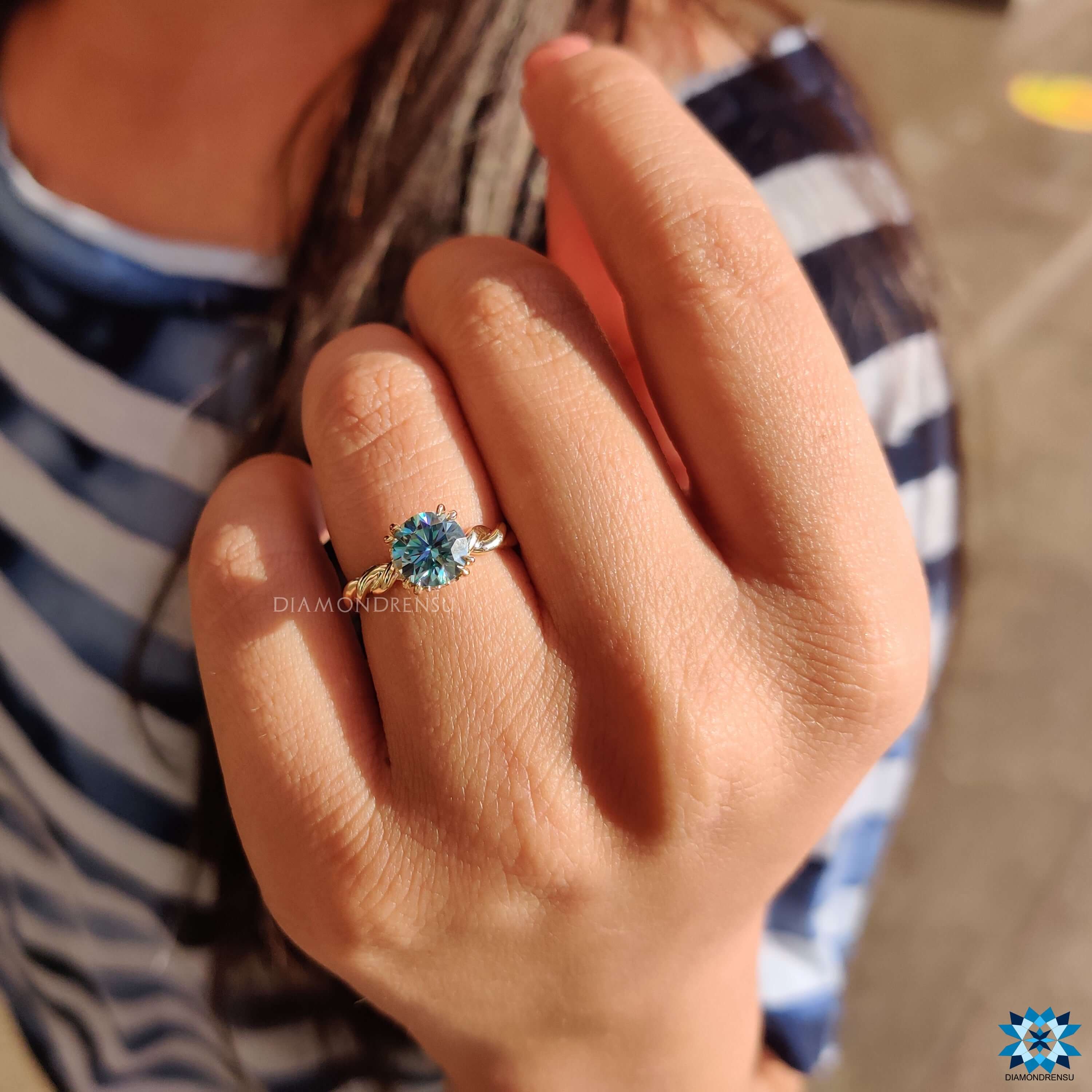 Cyan moissanite solitaire ring in yellow gold with prong setting.