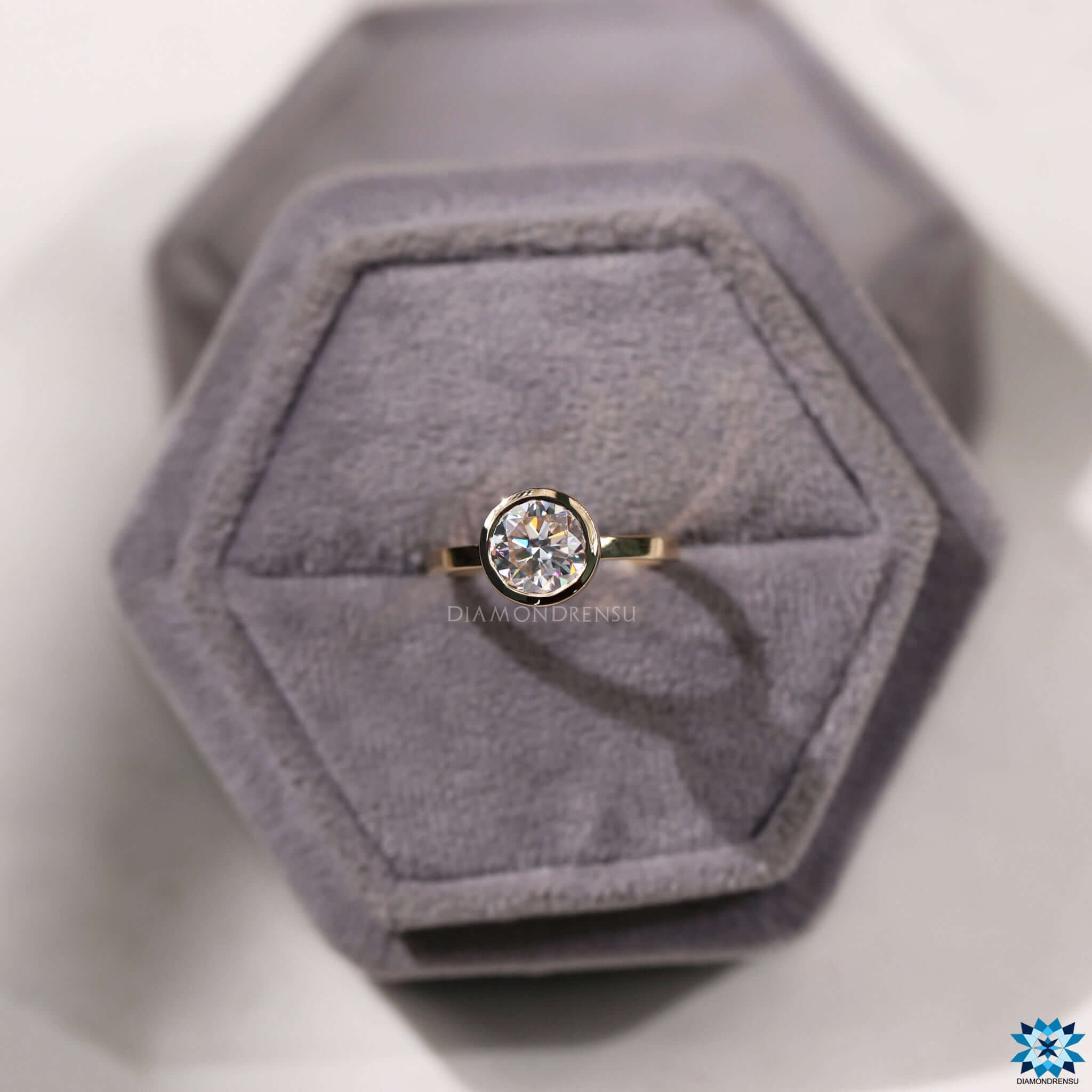 Custom engagement ring with bezel setting and round cut Moissanite in yellow gold.