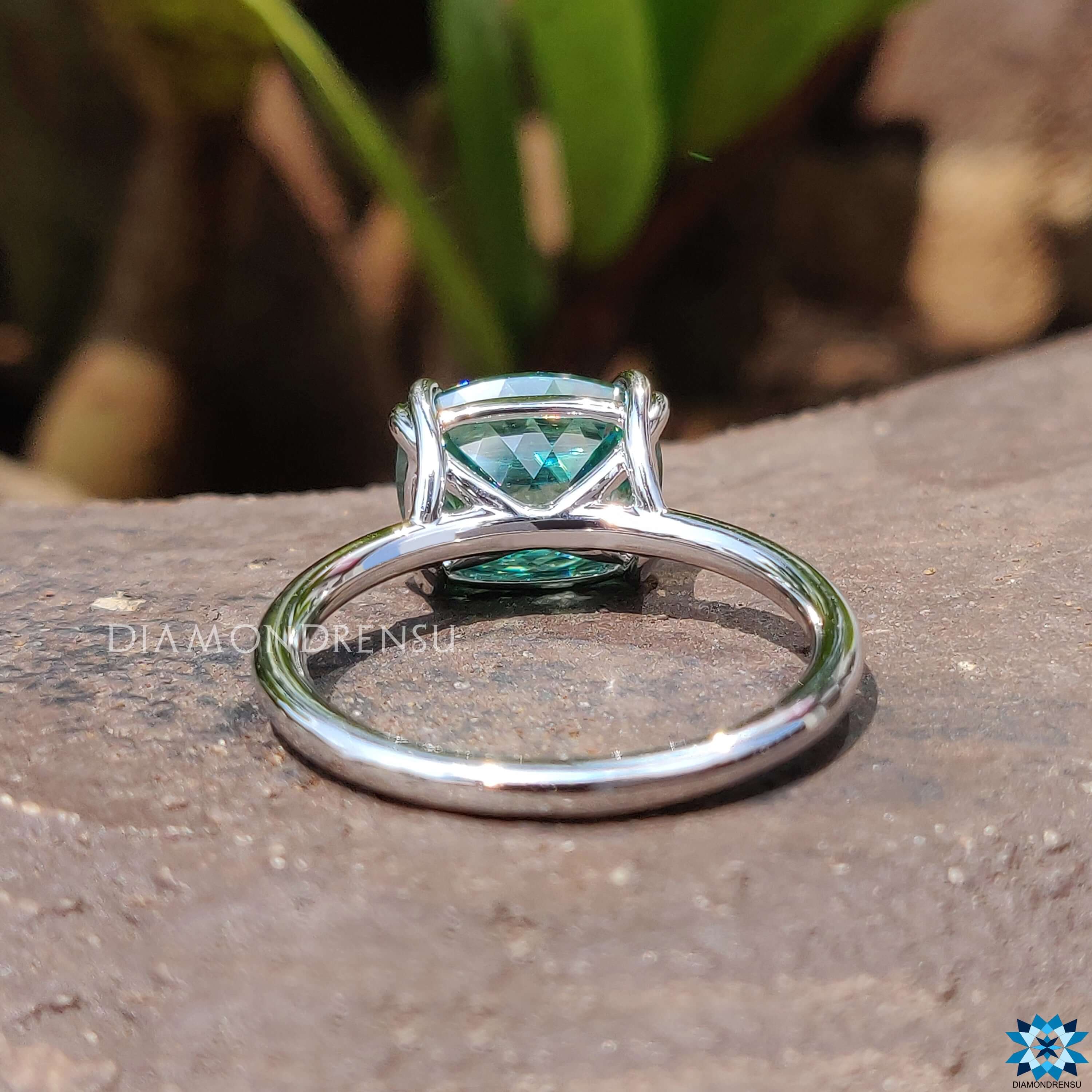 Cushion cut green moissanite in solitaire setting.