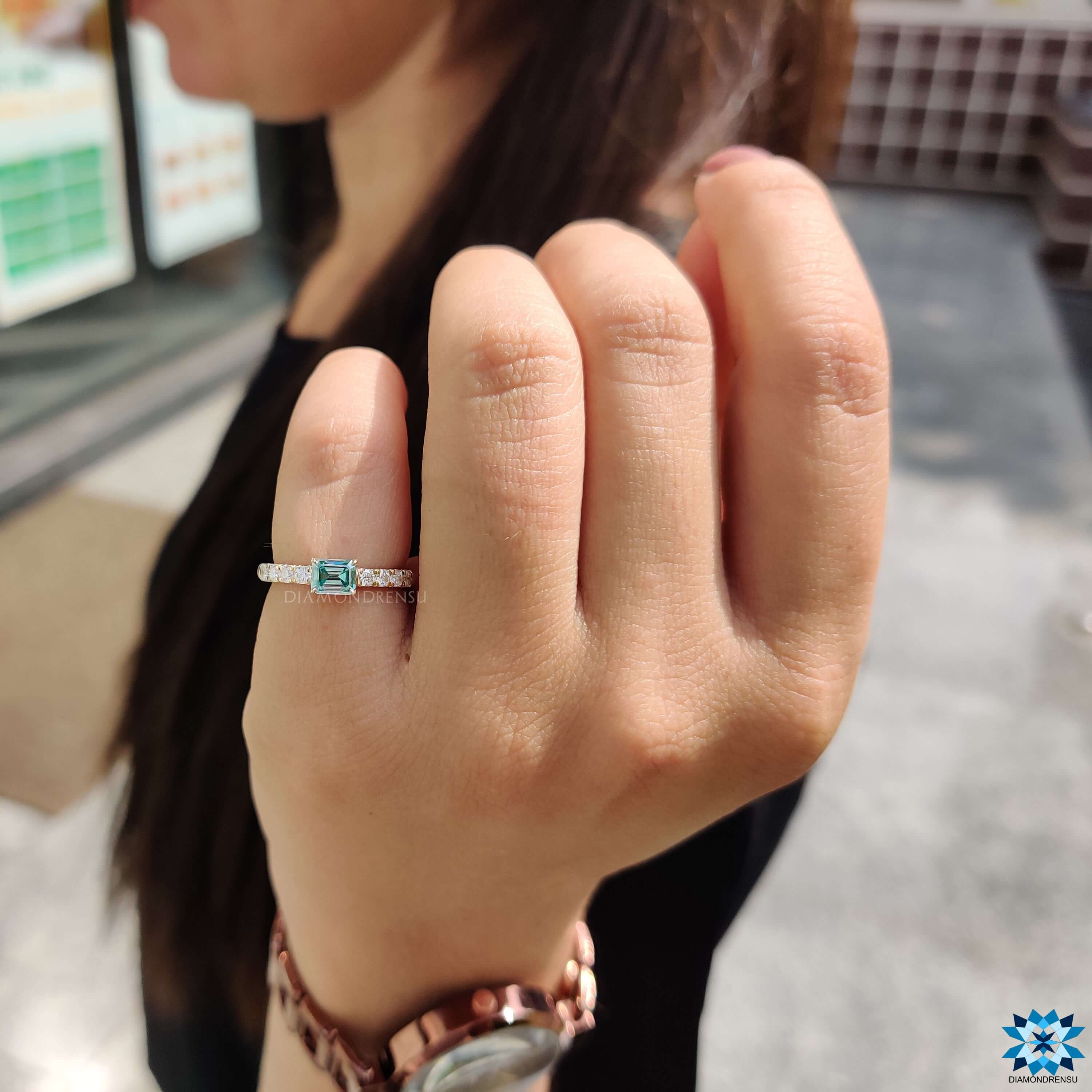 Emerald cut moissanite ring with pave setting.