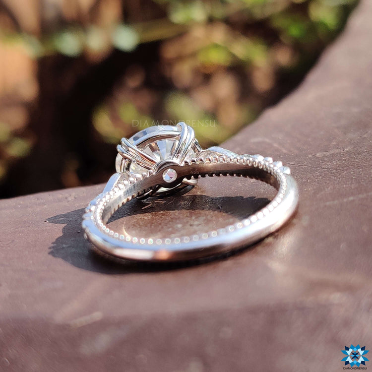 Milgrain setting engagement ring with oval moissanite centerpiece.