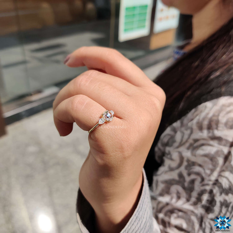 Round engagement ring with pear side stones and 4 prong setting.
