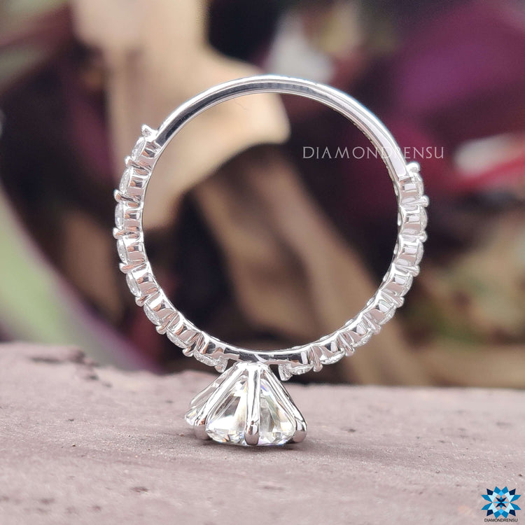 6 prong claw setting holding round moissanite on a pave band.