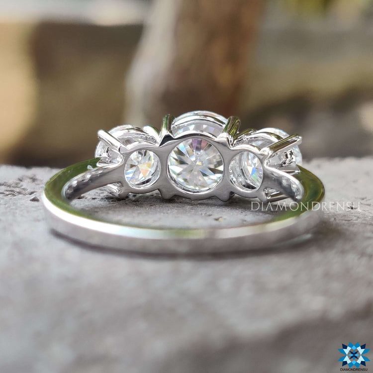 Moissanite engagement ring with round center and side stones.