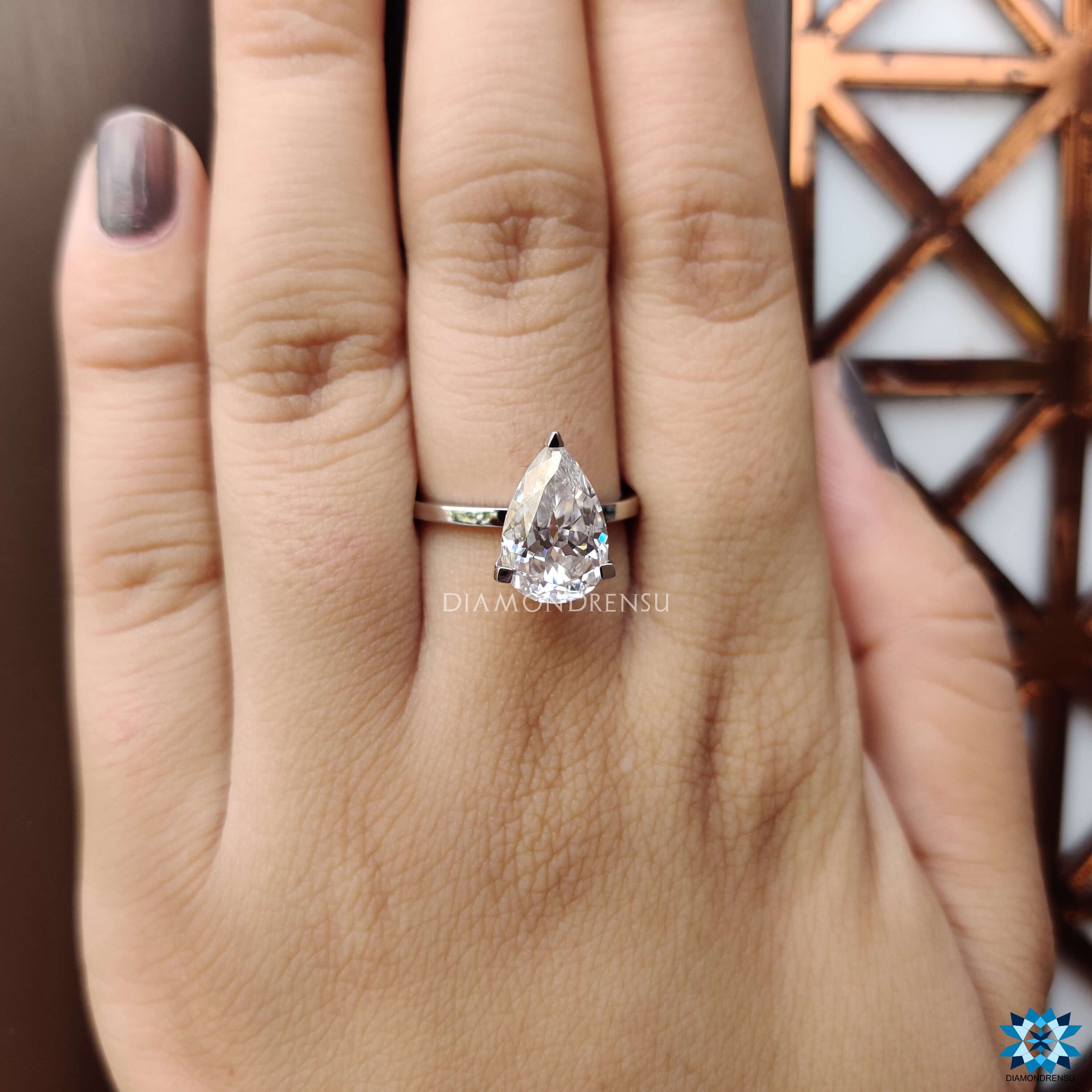 Simple solitaire setting with pear cut moissanite center.