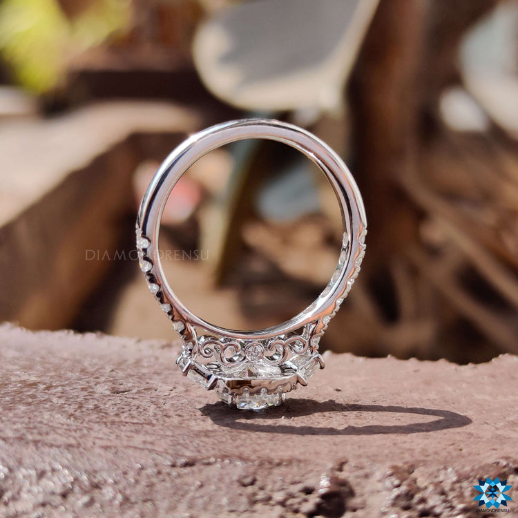 Filigree-inspired engagement ring with round cut center and pave band.
