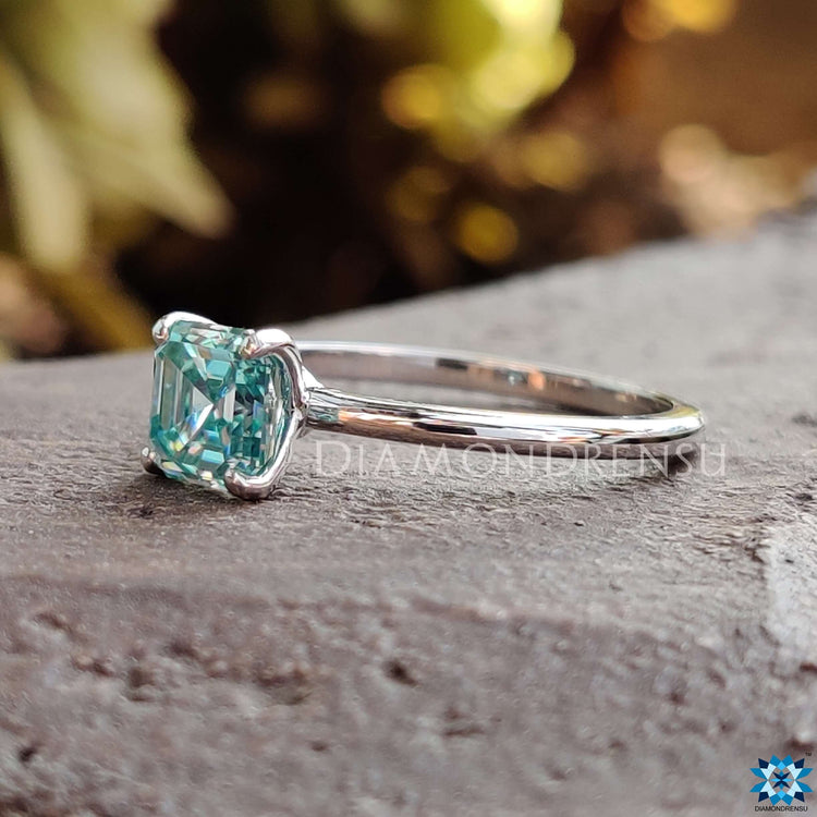 White gold ring with a cyan blue Asscher cut moissanite center.