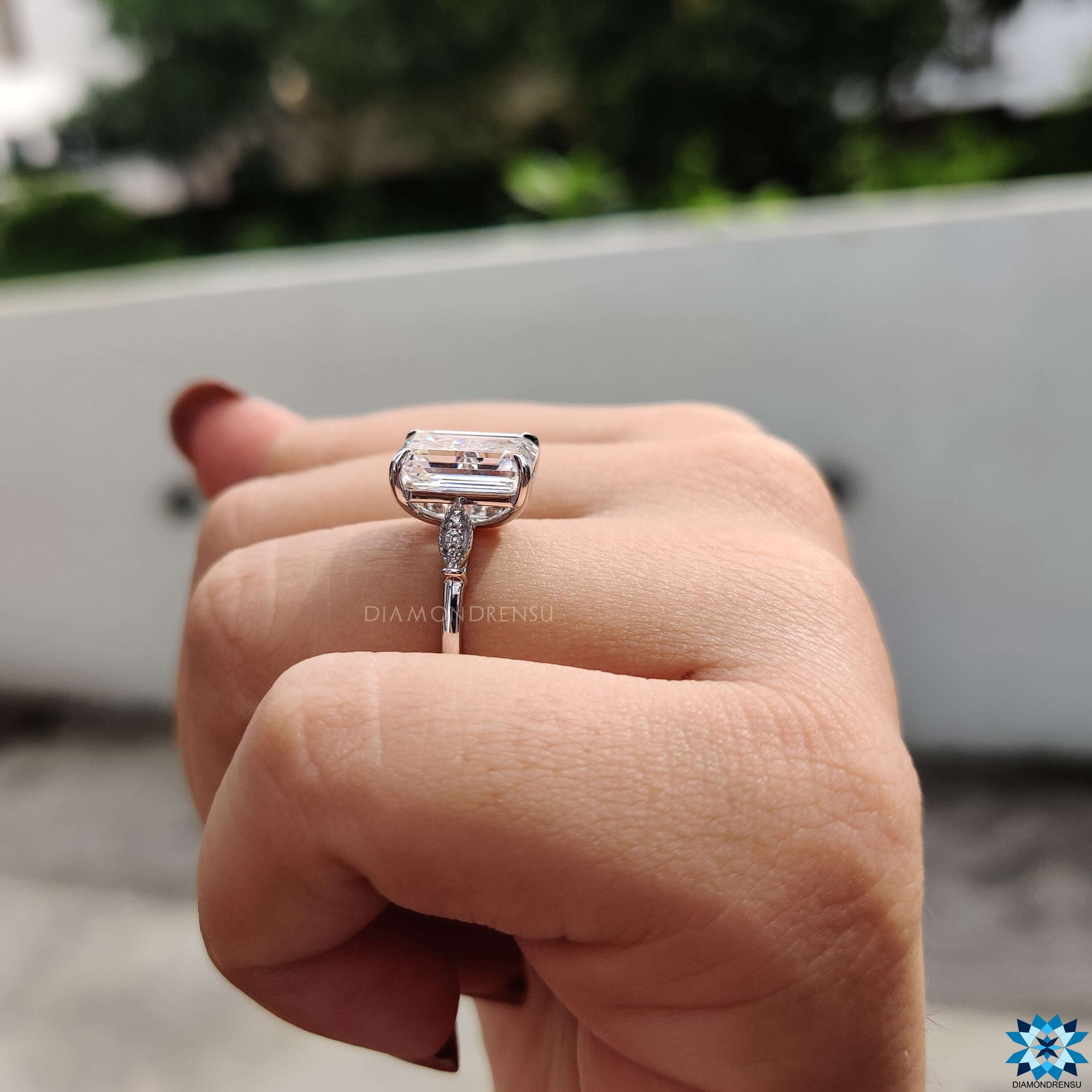 White gold ring with emerald center and marquise-style detail.