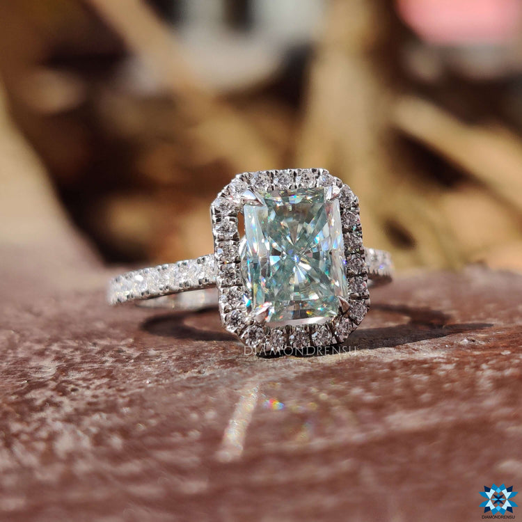 Moissanite halo engagement ring featuring a radiant cut center and pave set accents.
