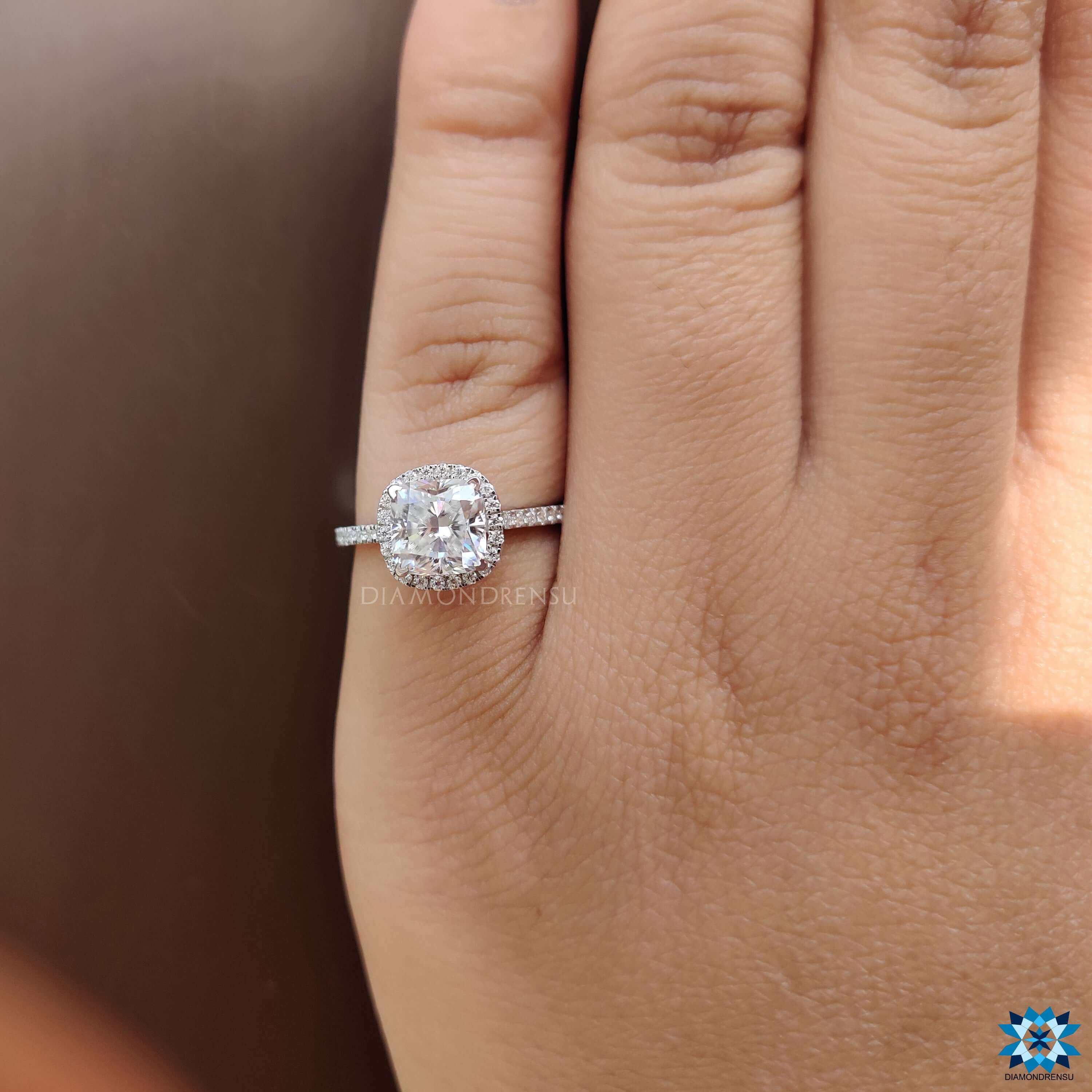 Cushion halo ring with round cut side stones and cathedral profile.