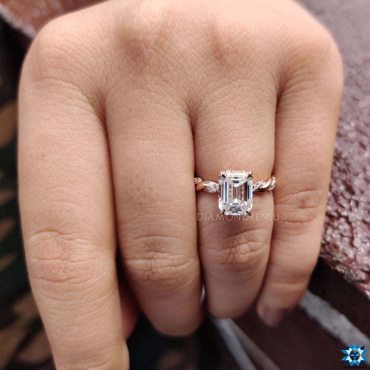 Rose gold ring featuring emerald center and twisted band.