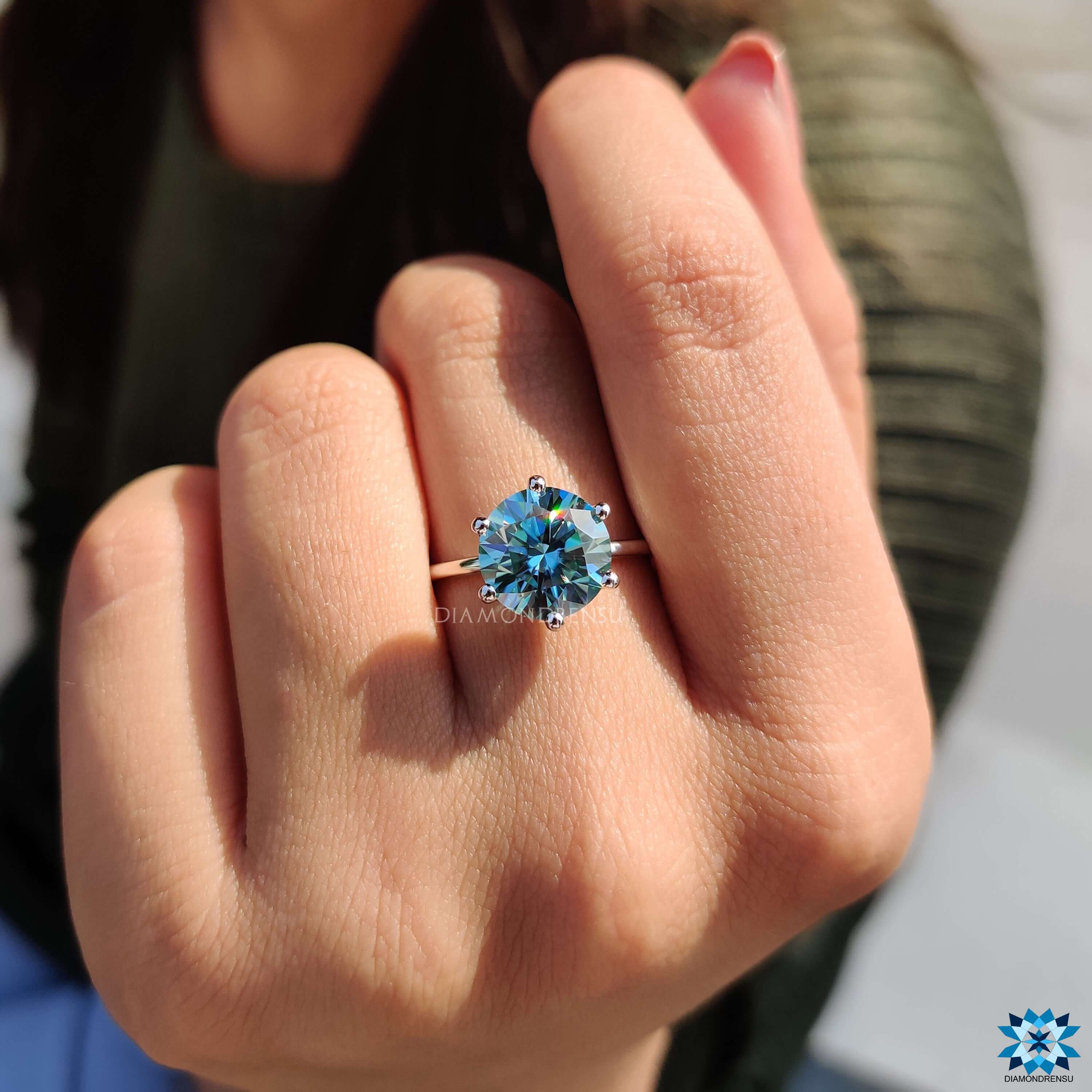 Solitaire engagement ring featuring a cyan blue moissanite center in a 6 prong mount.