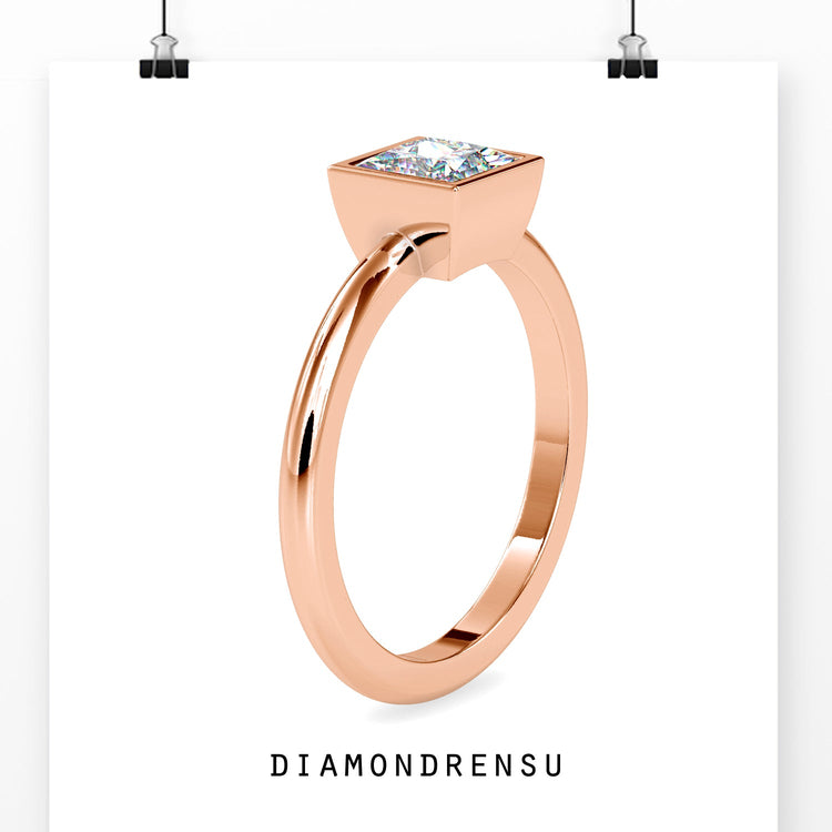 Solitaire diamond ring with bezel setting in yellow gold.