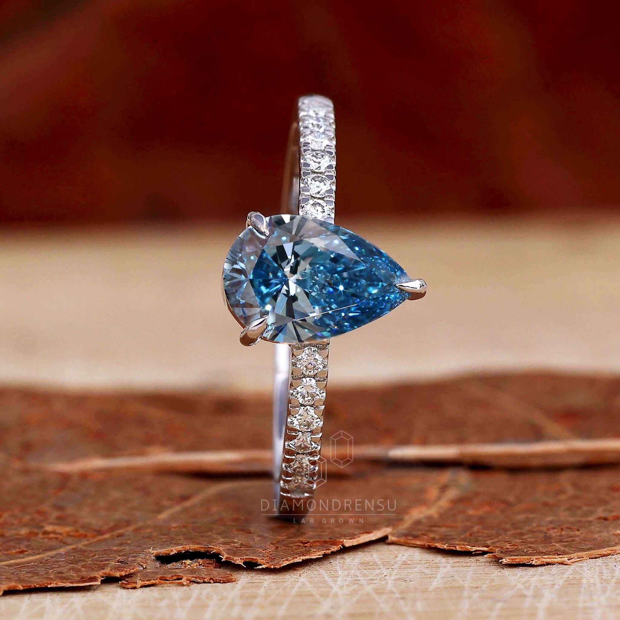 Pear shaped engagement ring with pave diamond accents, designed for sophisticated women.