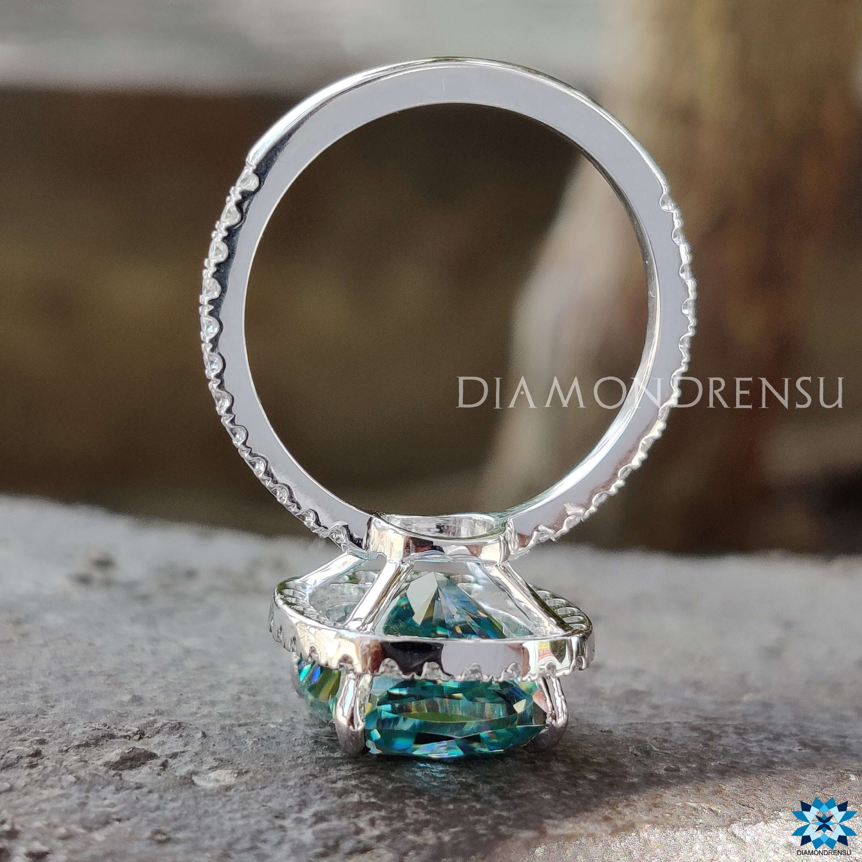 Moissanite engagement ring featuring cyan blue cushion cut stone with pave setting in white gold.