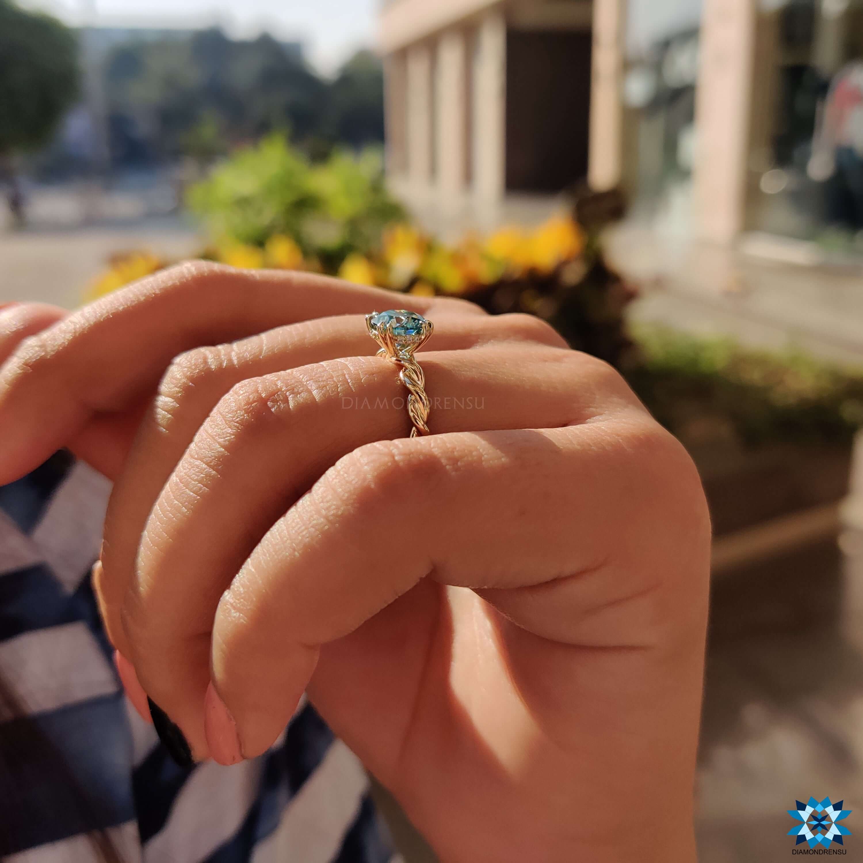 Round blue moissanite ring set in twisted yellow gold band.