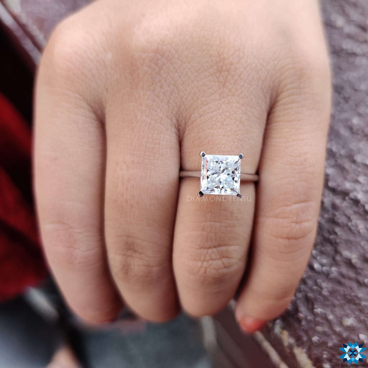 Solitaire engagement ring featuring a moissanite princess cut stone in a minimal design.