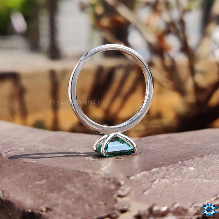 4 claw prong ring holding green moissanite.
