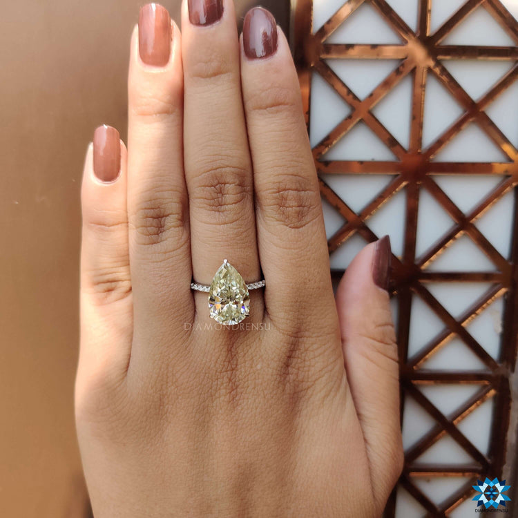 Pave set pear cut ring in light yellow moissanite with white gold finish.